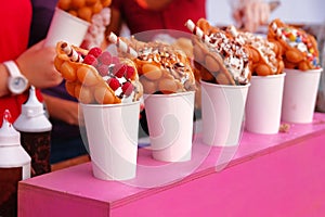 Bubble waffles with raspberries, chocolate and marshmallow in white paper cups are sold on Open kitchen food festival event.