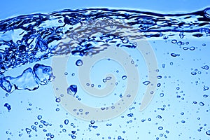 Bubbles of air under blue water and wave or splash