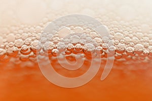 Bubbles from a beer froth close-up on half a glass.