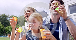 Bubbles, family and outdoor fun of mom, dad and girl together blowing bubble with care. Happy, garden and bonding of a