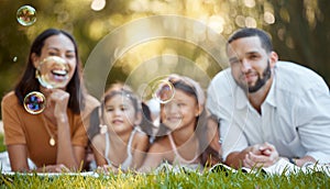 Bubbles, family and relax on grass at park, nature or outdoors on summer vacation. Happy portrait, smile and care of