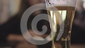 Bubbles movement inside a glass of beer with drops and foam as background.