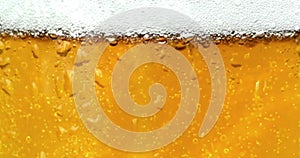 Bubbles movement inside a glass of beer with drops and foam as background