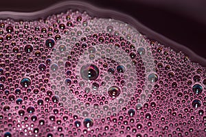 Bubbles of red wine closeup. Alcoholic background