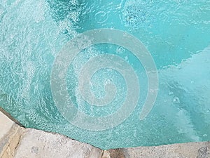 Bubbles in the turqoise water of a hot tub with rock rim top view photo