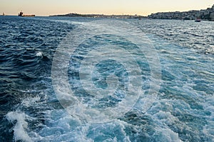 Bubbling blue waves of traces of tourist cruise ships passing on the Bosporus. Water trail foaming behind a passenger