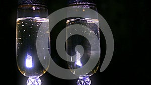Bubbling champagne being poured into two crystal glasses against black