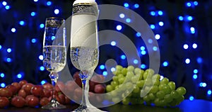 Bubbling champagne being poured into two crystal glasses against boke black backgroung