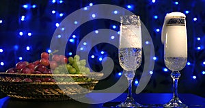 Bubbling champagne being poured into two crystal glasses against boke black backgroung