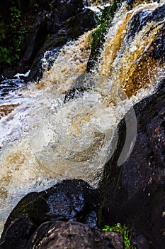 a bubbling fast cold river with cliffs and waterfalls, a mountain river with rapids