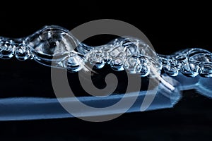 Bubbling glass cleaner in a transparent bottle on a black background. Abstraction. The concept of modern development of chemical