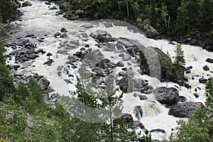 Bubbling stream of a mountain river with large stones, in a forest area. Top view on popple water photo