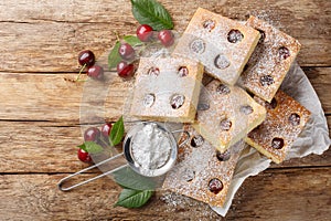 Bublanina Czech and Slovakian Cherry Bubble Cake with sprinkled with powdered sugar closeup on the parchment. Horizontal top view photo