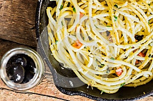 Bucatini pasta with cheese and a jar of olives