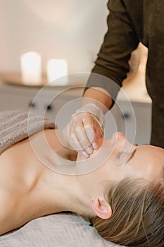 buccal facial massage, close-up, cosmetologist makes woman a procedure on a massage table in a spa salon