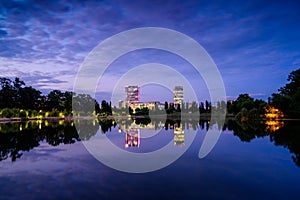 Bucharest office buildings at blue hour with lake reflection in summer time , Romania