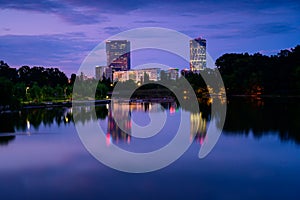 Bucharest office buildings at blue hour with lake reflection in summer time , Romania