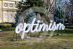 Bucharest, Romania, 2 January 2022: Optimism word displayed in front of the Romanian Atheneum Ateneul Roman)