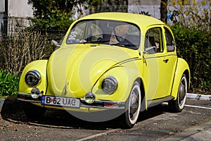 Bucharest, Romania, 2 April 2021 Old retro yellow Volkswagen Beetle classic car parked a street in a sunny spring day