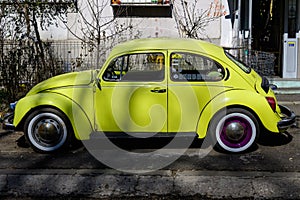 Bucharest, Romania, 3 March 2021 Old retro yellow Volkswagen Beetle classic car parked a street in a sunny spring day