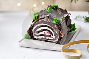 Buche de Noel. Traditional Christmas dessert, Christmas yule log cake with chocolate cream. Christmas tree branches.