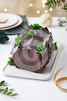 Buche de Noel. Traditional Christmas dessert, Christmas yule log cake with chocolate cream. Christmas tree branches.