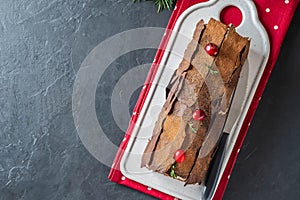 Buche de Noel. Traditional Christmas dessert, Christmas yule log cake with chocolate cream, cranberry. On stone gray