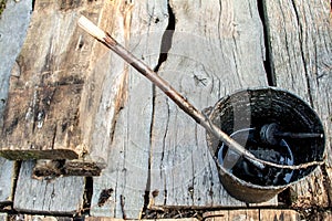 A bucket of black tar boils on the fire for use in repair and waterproofing.