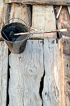 A bucket of black tar boils on the fire for use in repair and waterproofing.