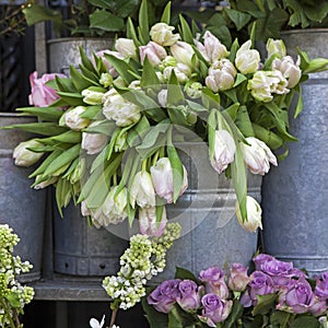 The bucket with a bouquet of white tulips and a vase with red roses as a decoration for the entrance of the house