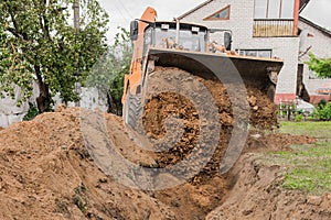 A bucket of a bulldozer fills the trench with earth in an industrial zone. Excavation construction works