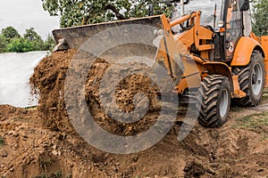 A bucket of a bulldozer fills the trench with earth in an industrial zone. Excavation construction works