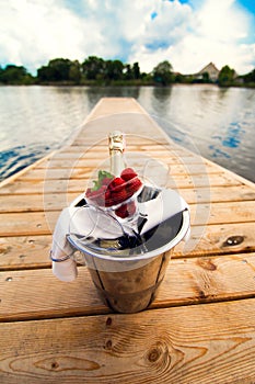 Bucket with champagne and berries on the pier