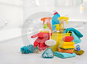 Bucket with chemical products on table over blurred bathroom background