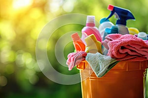 A bucket of cleaning products on a blurred green background: cleaning wipes, rags and bottles. The concept of cleanliness and