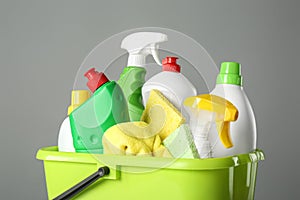 Bucket with cleaning products and tools on grey background, closeup