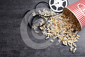 Bucket of fresh popcorn and movie reel on stone table, flat lay with space for text. Cinema snack