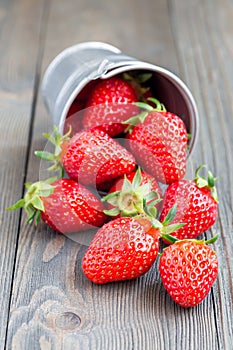 Bucket full of strawberries lying on a wooden background