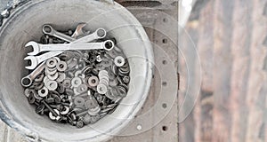 A bucket full of wrenches, washers and stud bolts is placed on the scaffolding