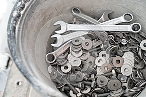 A bucket full of wrenches, washers and stud bolts is placed on the scaffolding