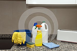 Bucket, gloves, rag, scouring pad and cleaning supplies on the kitchen table