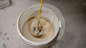 A bucket of hedgehog paint mixing in motion. A painter mixes paint using a bucket mixer. Mixing paint in a bucket.