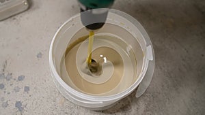 A bucket of hedgehog paint mixing in motion. A painter mixes paint using a bucket mixer. Mixing paint in a bucket.