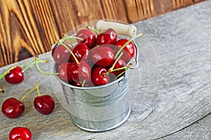 A bucket ith cherrys on wooden background photo