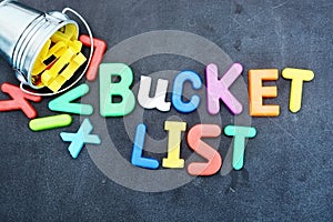 Bucket list concept, things to do in life with iron bucket and magnetic letters on chalkboard