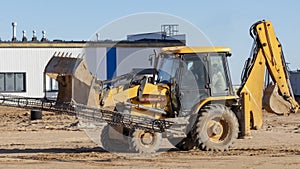 A bucket loader carries out loading of coal in an open port warehouse on a background of black mountains of coal