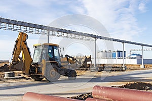 A bucket loader carries out loading of coal in an open port warehouse on a background of black mountains of coal