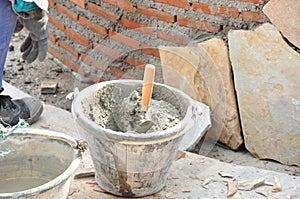 Bucket of mortar with trowel beside constructing brick wall photo