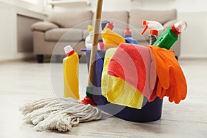 Bucket with sponges, chemicals bottles and mopping stick.