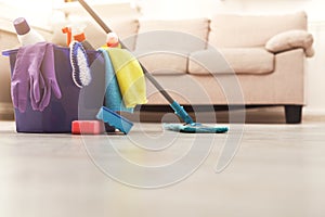 Bucket with sponges, chemicals bottles and mopping stick.